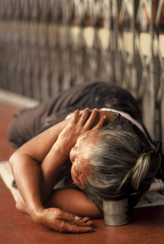 Photo of lady sleeping in street with head on a can in Penang, Malaysia by Ron Veto /></div>
<p style=